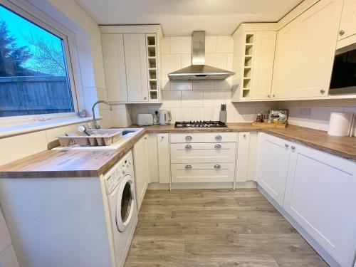 a white kitchen with a sink and a dishwasher at Haven lovely home just off M20 in great area & parking in Kent