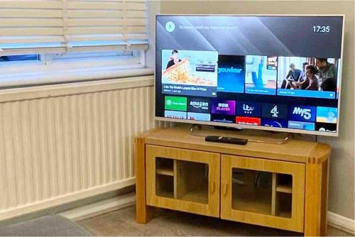 a flat screen tv sitting on top of a wooden stand at Haven lovely home just off M20 in great area & parking in Kent