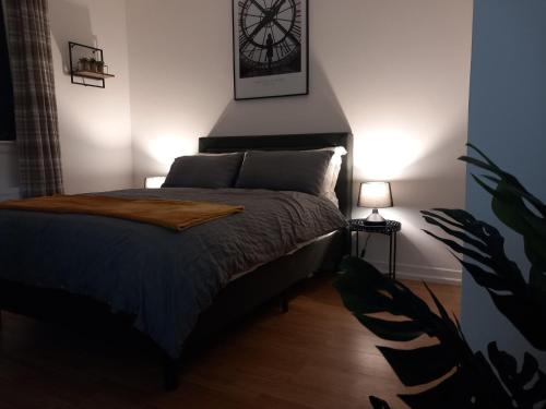 a bedroom with a bed with a clock on the wall at Douglas Apartment - Trains to Edin & Glasgow - Private Parking in Airdrie