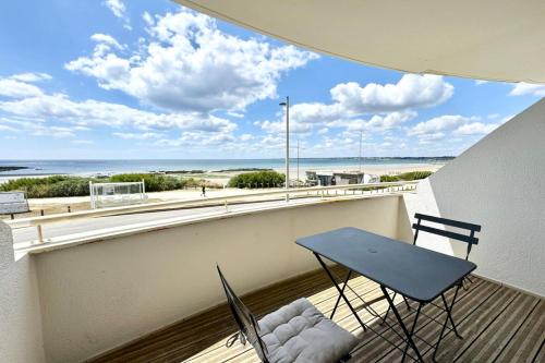 une table et des chaises sur un balcon avec vue sur la plage dans l'établissement Superbe T2 Ultra cocooning - Vue mer 180, à Ploemeur