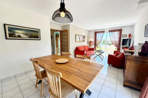a dining room and living room with a wooden table at Charmante maison de vacances entre bourg et plages in Ploemeur