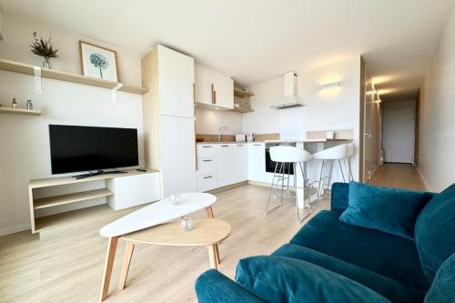 un salon avec un canapé bleu et une cuisine dans l'établissement Superbe T2 Ultra cocooning - Vue mer 180, à Ploemeur