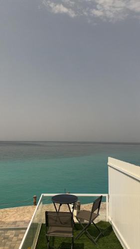 a table and chairs on a balcony with the ocean at Wadi Shab Beach Villa in Sur