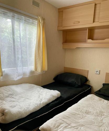 deux lits dans une petite pièce avec une fenêtre dans l'établissement Mobilhome BA281 - Small budget - Siblu Bonne Anse Plage, aux Mathes