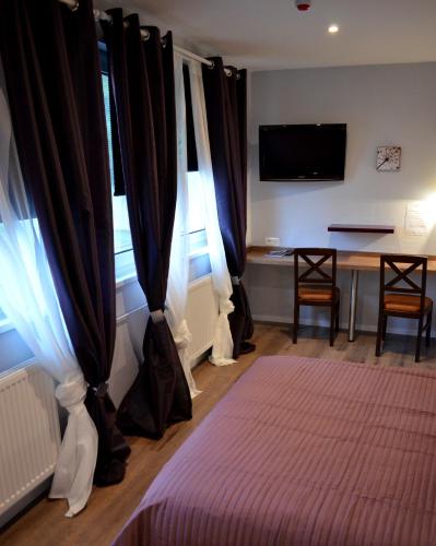 a bedroom with a bed and a table and a television at Hôtel Restaurant La Couronne in Roppenheim