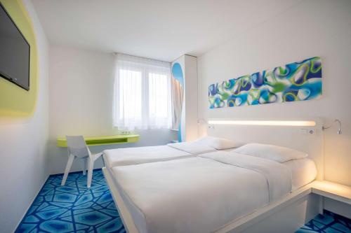 a white bedroom with a bed and a desk at Prize by Radisson, Hamburg City in Hamburg