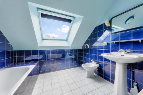 La salle de bains est pourvue de carrelage bleu, d'un lavabo et de toilettes. dans l'établissement Arzon, maison et son grand jardin pour 6 personnes, à Arzon