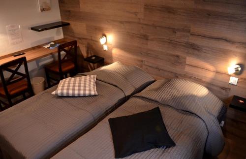 two beds in a room with wooden walls at Hôtel Restaurant La Couronne in Roppenheim