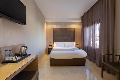a hotel room with a bed and a television at Gran Hotel Barcino in Barcelona