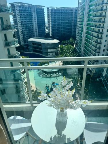 a vase of flowers on a table on a balcony at Manila Azure Staycation By Via & Sabby in Manila