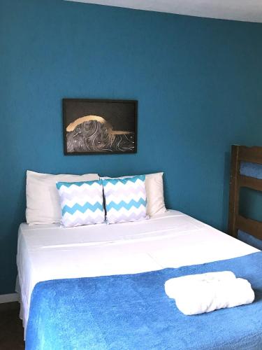 a bedroom with a white bed with a blue wall at Pousada Turquesa By Gente Bonita in Búzios