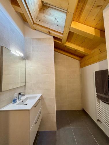 La salle de bains est pourvue d'un lavabo et d'un plafond en bois. dans l'établissement Grand T3 et Coin montagne central et lumineux - Multipass inclu, à Châtel