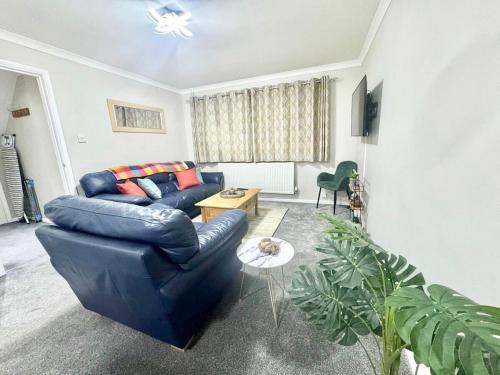 a living room with a blue couch and a table at Lovely modern 4 bedroom House in Ashford in Ashford