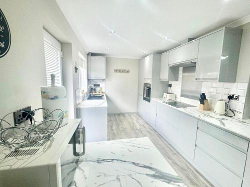 a large white kitchen with white cabinets and appliances at Lovely modern 4 bedroom House in Ashford in Ashford