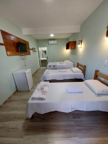 a room with three beds and a flat screen tv at Pousada Tia Rosa in Parnamirim