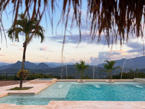 a swimming pool with a palm tree and mountains in the background at Fina Estampa Country Hotel by HMC - Mayores de 10 años - in Támesis