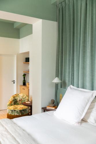 a bedroom with a bed and a chair and green curtains at Bellevigne Bourgogne in Chambolle-Musigny