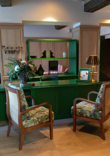 a lobby with a green desk with two chairs at Bellevigne Bourgogne in Chambolle-Musigny