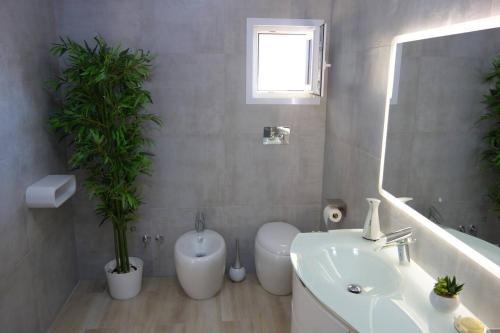 a bathroom with a sink and a toilet and a mirror at Guest House - La bella vita in Orosei