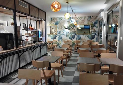 a restaurant with tables and chairs and a wall of plants at B&B HOTEL Agen Castelculier in Castelculier