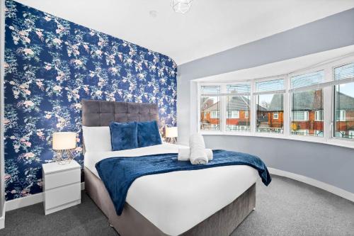 a bedroom with a large bed with blue and white wallpaper at Stylish 3 Bedroom House - Parking - Garden - Great Barr - Netflix - Top Rated -121J in Birmingham