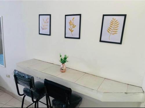 een witte tafel met vier foto's aan een witte muur bij Apartamento Las Aldabas in Chihuahua