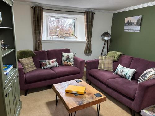 a living room with two purple couches and a table at Traditional 2 bed croft in Portskerra