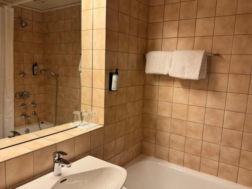 a bathroom with a tub and a sink and a mirror at Park Hotel Vossevangen in Vossevangen