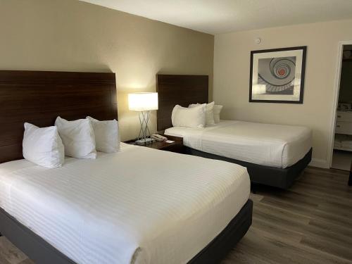 a hotel room with two beds and a lamp at All-New, Heated Pool, Tiki Bar & Grill, Great Wifi in Sarasota