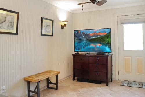 a living room with a tv on a dresser with a bench at Off The Hook by Pristine Properties Vacation Rentals in Saint Joe Beach