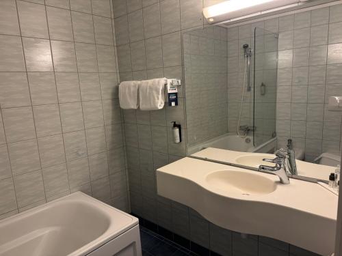 a bathroom with a sink and a tub and a mirror at Park Hotel Vossevangen in Vossevangen
