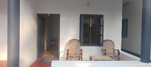 due sedie di vimini sedute su un portico con porta di Kaswa Beach Resort a Varkala