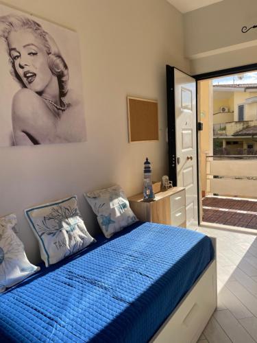 a bedroom with a blue bed with a painting on the wall at Alloggio fronte mare Melodia delle Onde in Ladispoli