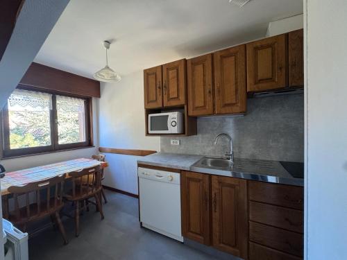 une cuisine avec des armoires en bois, un évier et une table dans l'établissement Lacroisette, à Gérardmer