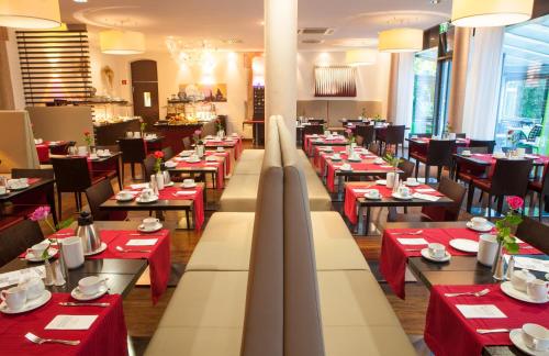 a dining room with red tables and chairs at Novina Hotel Tillypark in Nürnberg
