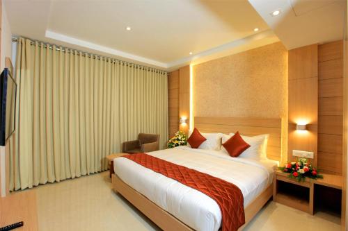 a hotel room with a bed and a television at RAAS Residency in Cochin