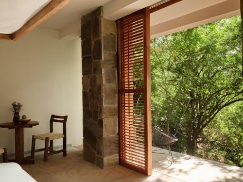 a bedroom with a large window with wooden shutters at Cocolia Hotel in Mazunte