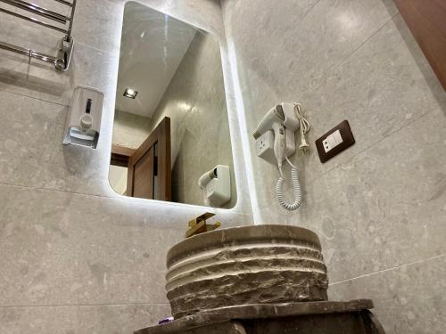 a bathroom with a mirror and a phone on the wall at Shiny Pyramids Boutique Hotel in Cairo