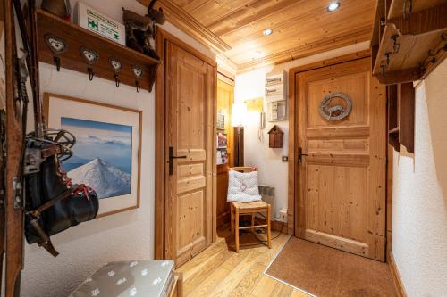 un couloir d'une cabine avec une porte et une chaise dans l'établissement Le Châtelard, à Val dʼIsère