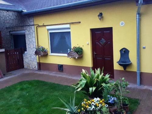 a yellow house with a door and some flowers at Green Lake Airport Apartments in Vecsés