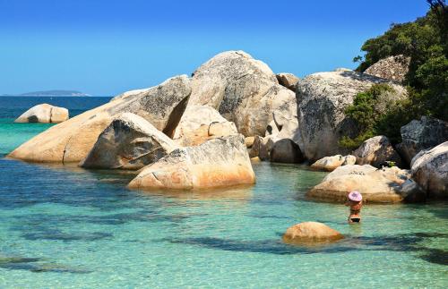 a person standing in the water near some rocks at U Caseddu in Sotta