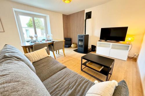 un salon avec un canapé, une table et une télévision dans l'établissement Maison entièrement rénovée - À 2 pas des plages, à Ploemeur