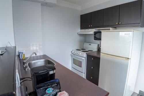 a kitchen with a white refrigerator and a sink at Century Plaza Hotel in Vancouver