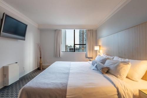 a bedroom with a large white bed with a large window at Century Plaza Hotel in Vancouver