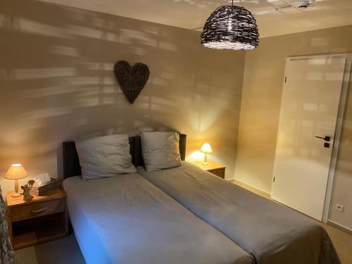 a bedroom with a bed with a heart on the wall at Gîte Le Chalet Suisse Dion in Beauraing