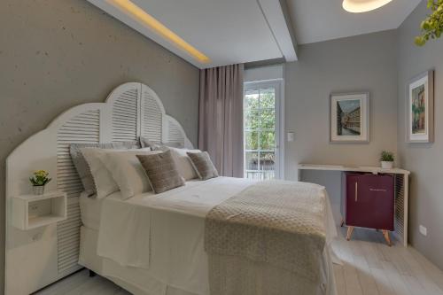 a bedroom with a large white bed and a window at Solar Beach Hotel in Florianópolis