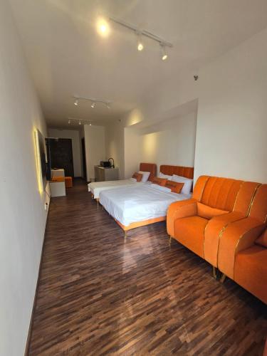 a bedroom with two beds and an orange couch at K Avenue Kota Kinabalu by Merveille - Sabah in Donggongon