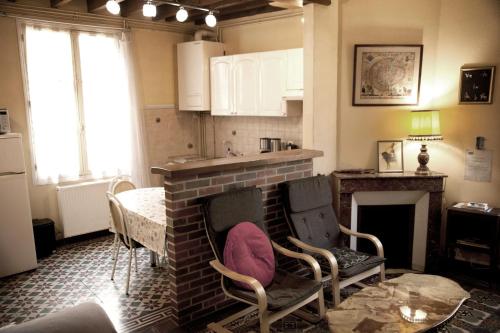 une cuisine avec une cheminée en briques, des chaises et une table dans l'établissement Maison accueillante à Auxerre de 50 m² avec jardin, à Auxerre