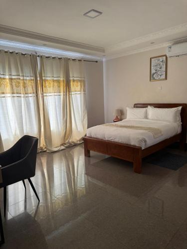 a bedroom with a bed and a chair and curtains at Eleganciana Lodges Limited in Lusaka