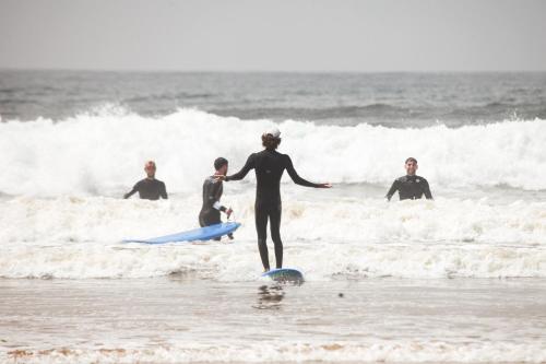 a woman is standing on a surfboard in the ocean at Tawala House shared dorm room in Agadir